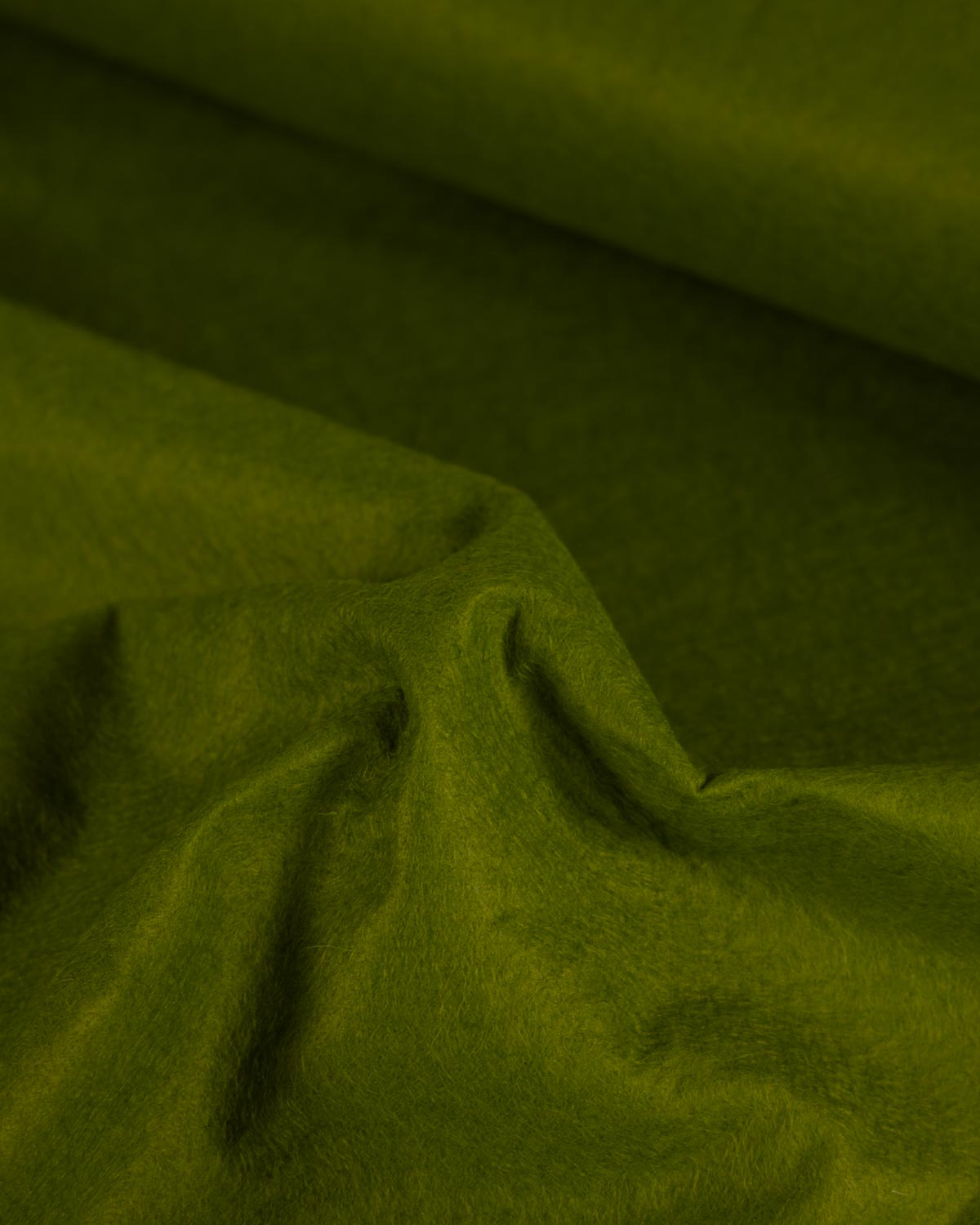 A close-up of moss green wool and viscose felt fabric with soft folds and a slightly textured surface.