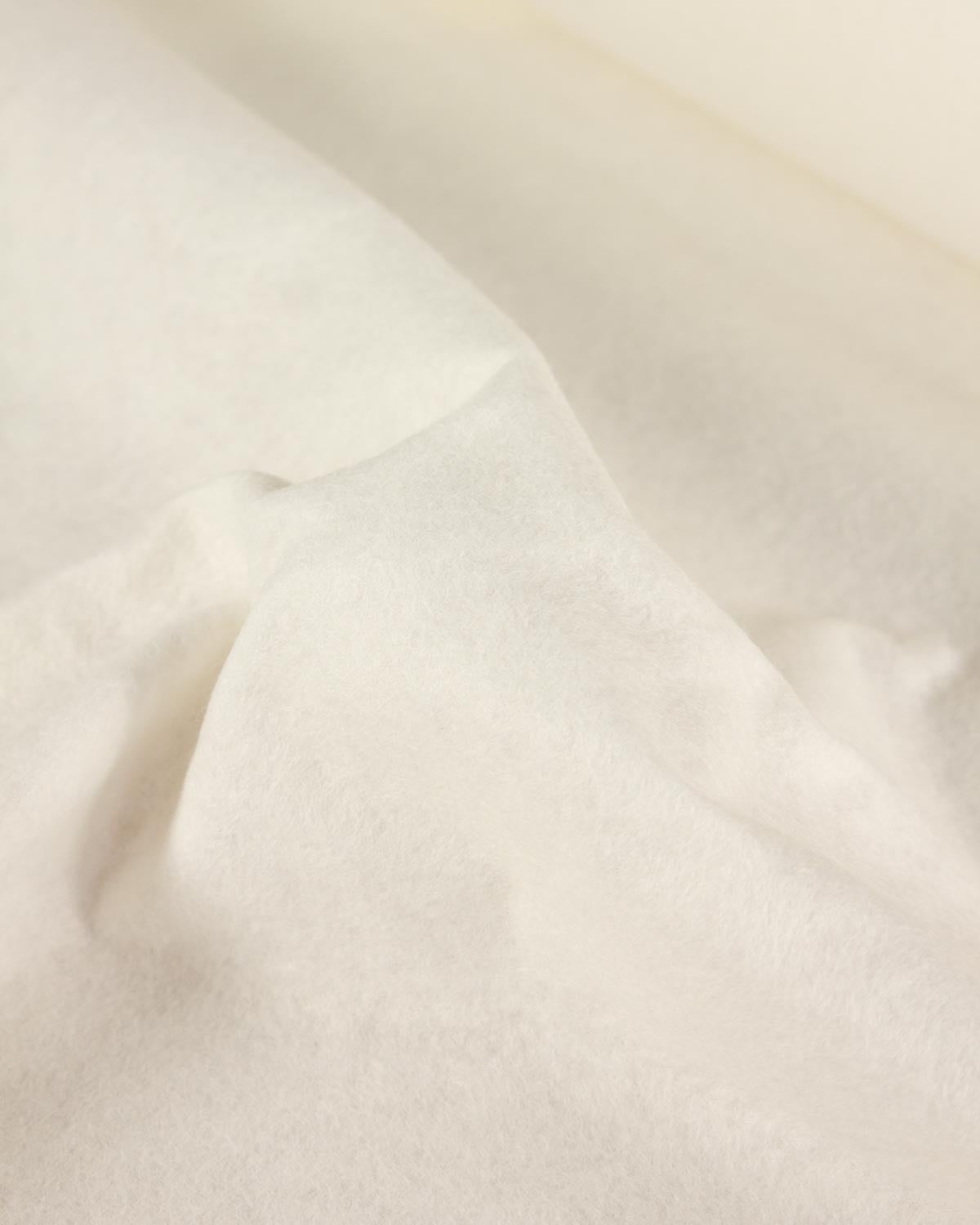A close-up of soft, draped off-white natural wool and viscose felt fabric with a smooth, slightly textured surface.