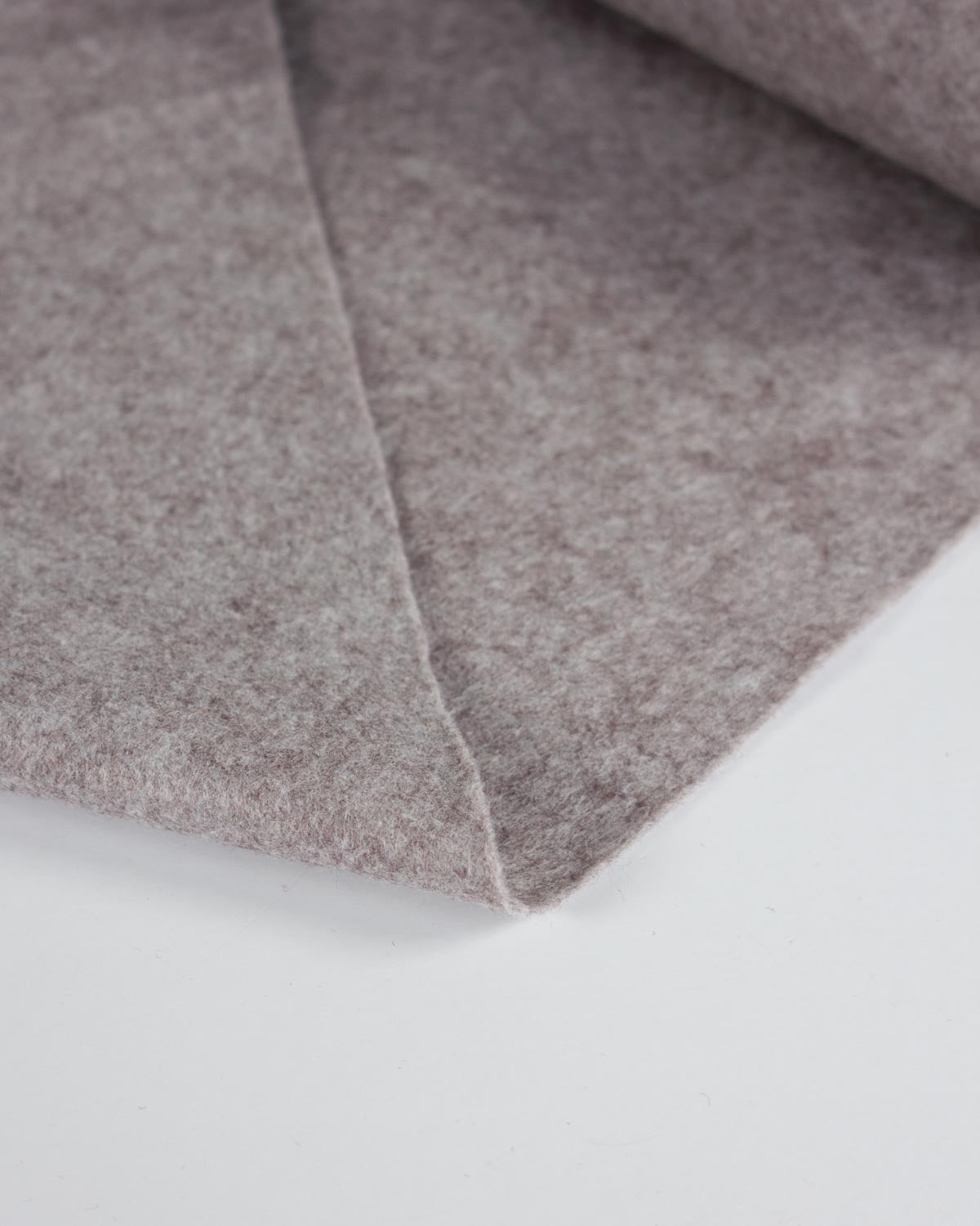 A piece of grey marl wool and viscose felt fabric folded on a flat white surface, showing its texture. 