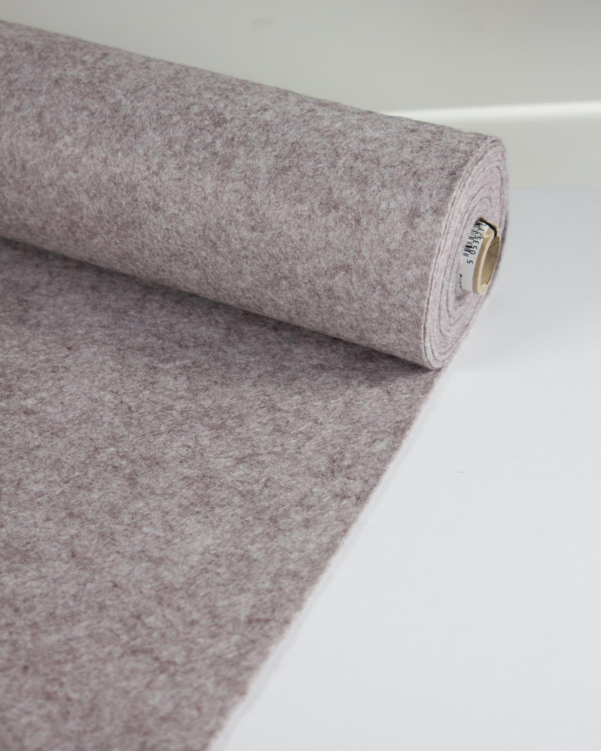 A roll of textured wool and viscose felt fabric in a dusty gray marl color, partially unrolled on a clean white surface.