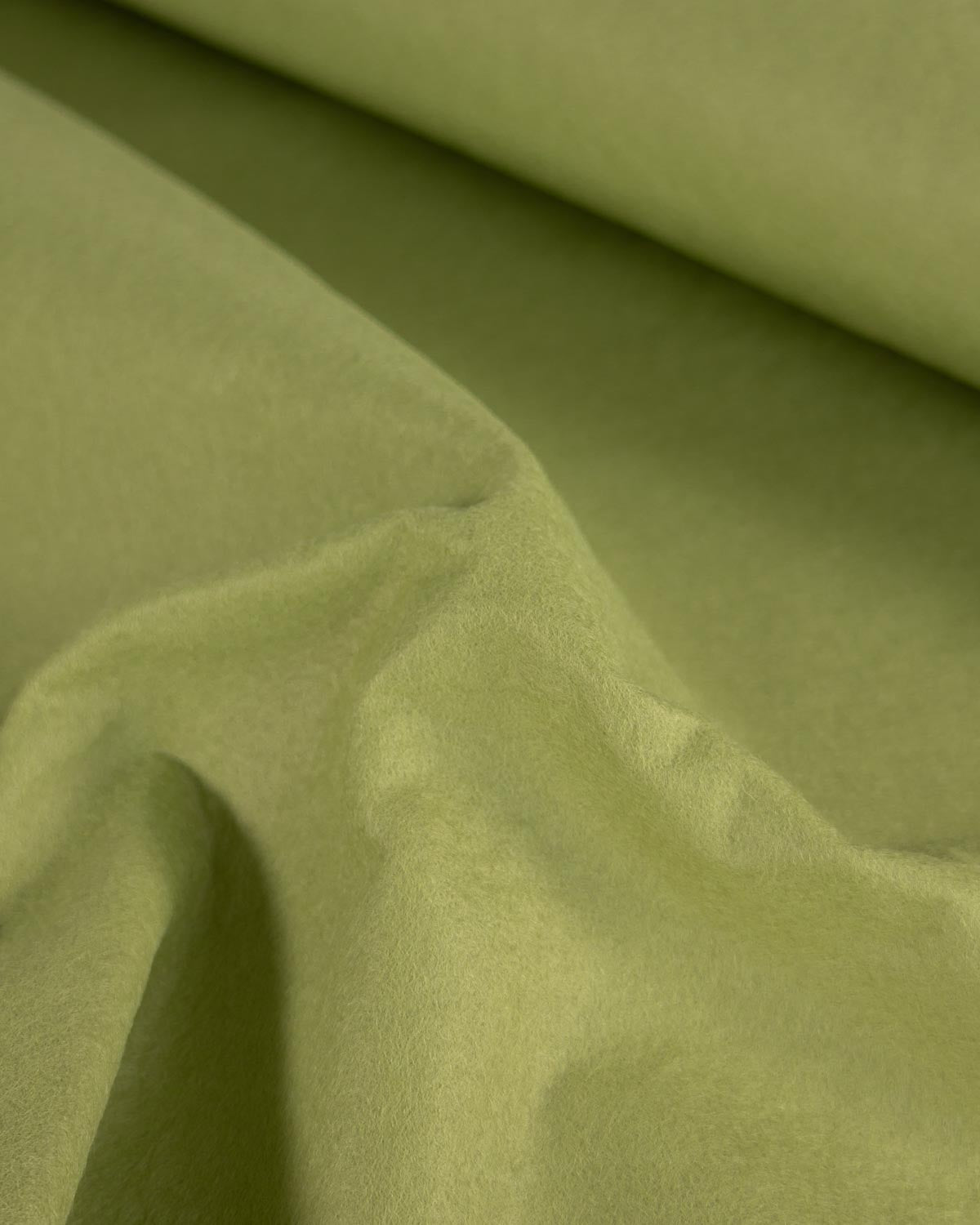 A close-up of meadow marl green wool and viscose felt fabric with soft folds and a matte texture, filling the entire frame.