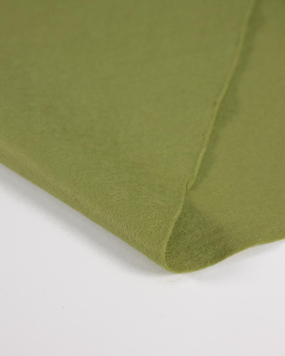A close-up of green meadow marl wool and viscose felt fabric folded over on a white surface, showing the material texture and color.