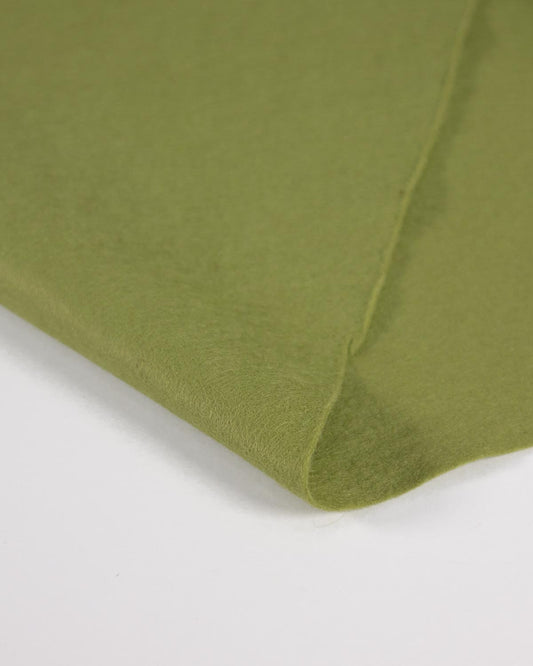 A close-up of green meadow marl wool and viscose felt fabric folded over on a white surface, showing the material texture and color.