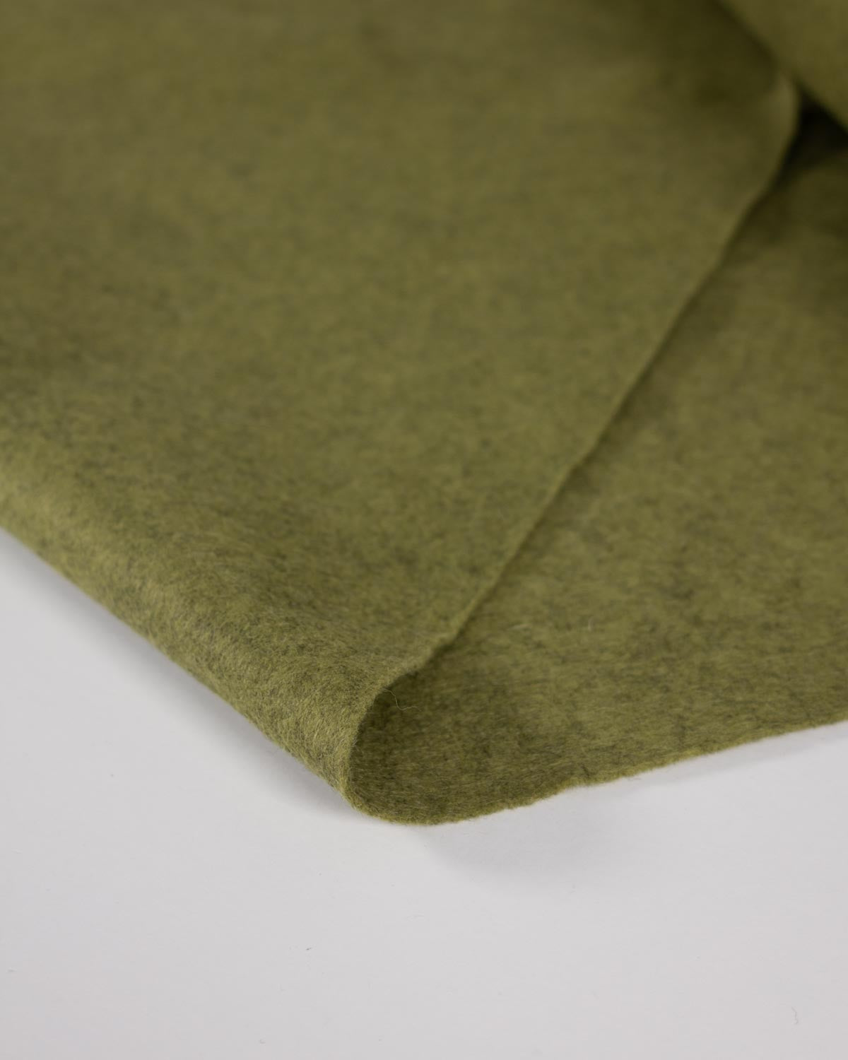 A close-up of moss green wool and viscose felt marl wool and viscose fabric folded over on a plain white background.
