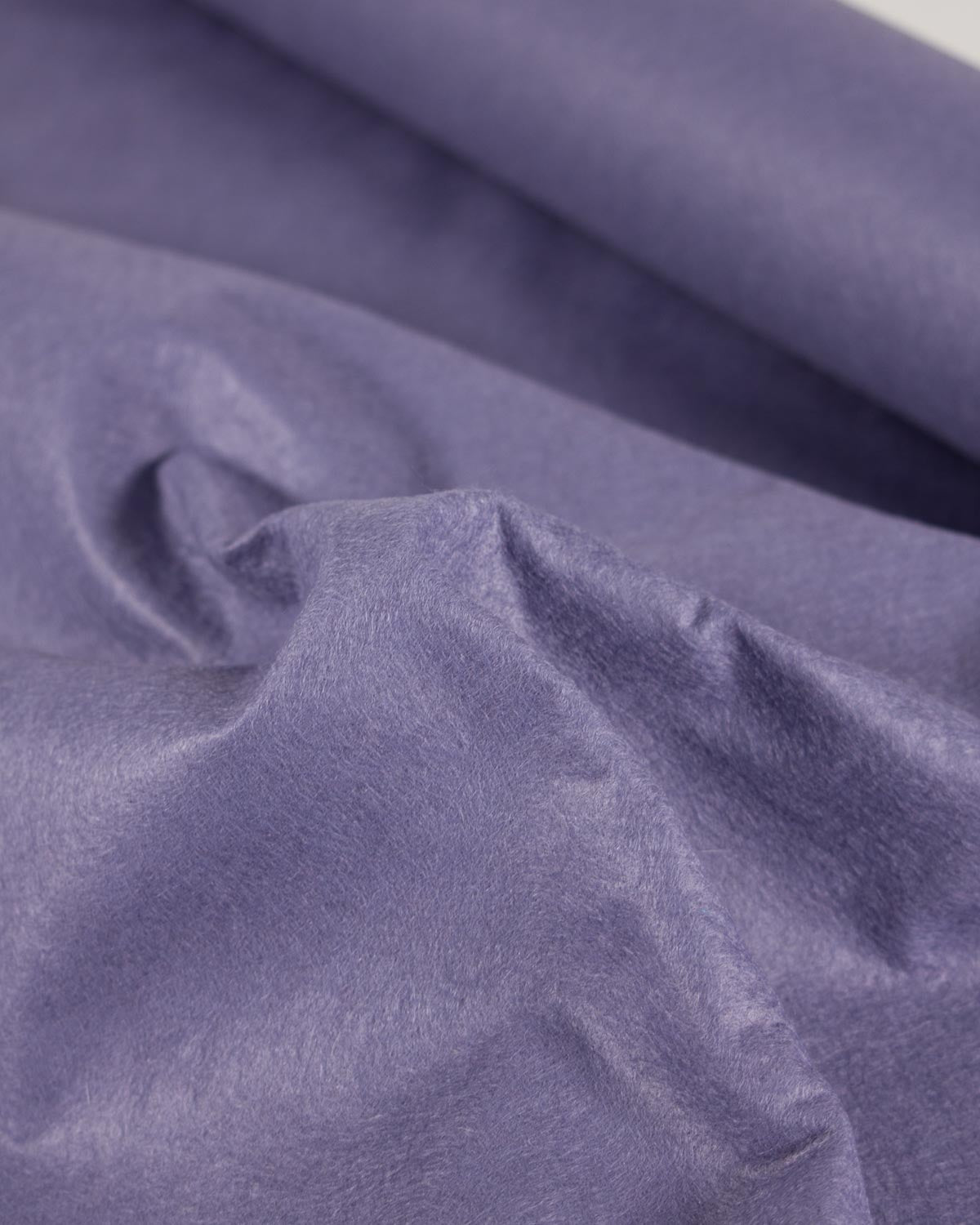 A close-up of draped lavender-purple wool blend craft felt fabric with a soft, slightly textured surface.