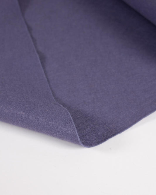 A close-up of wool blend craft felt fabric in a muted purple or dusty violet color, showing the texture and drape against a plain white background.