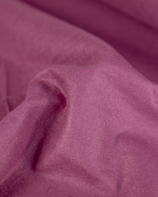 A close-up of draped raspberry pink/purple colored wool and viscose felt fabric with a soft, slightly fuzzy texture.