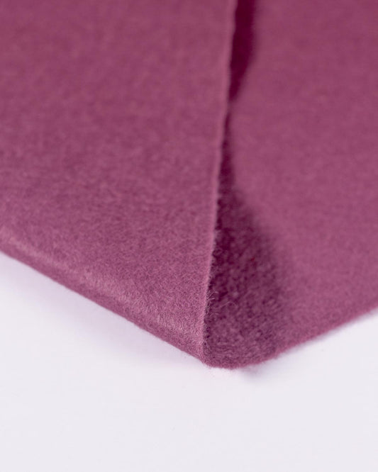 A close-up of a folded piece of raspberry pink/purple wool and viscose felt fabric on a clean white background, showing its even colour and texture. 