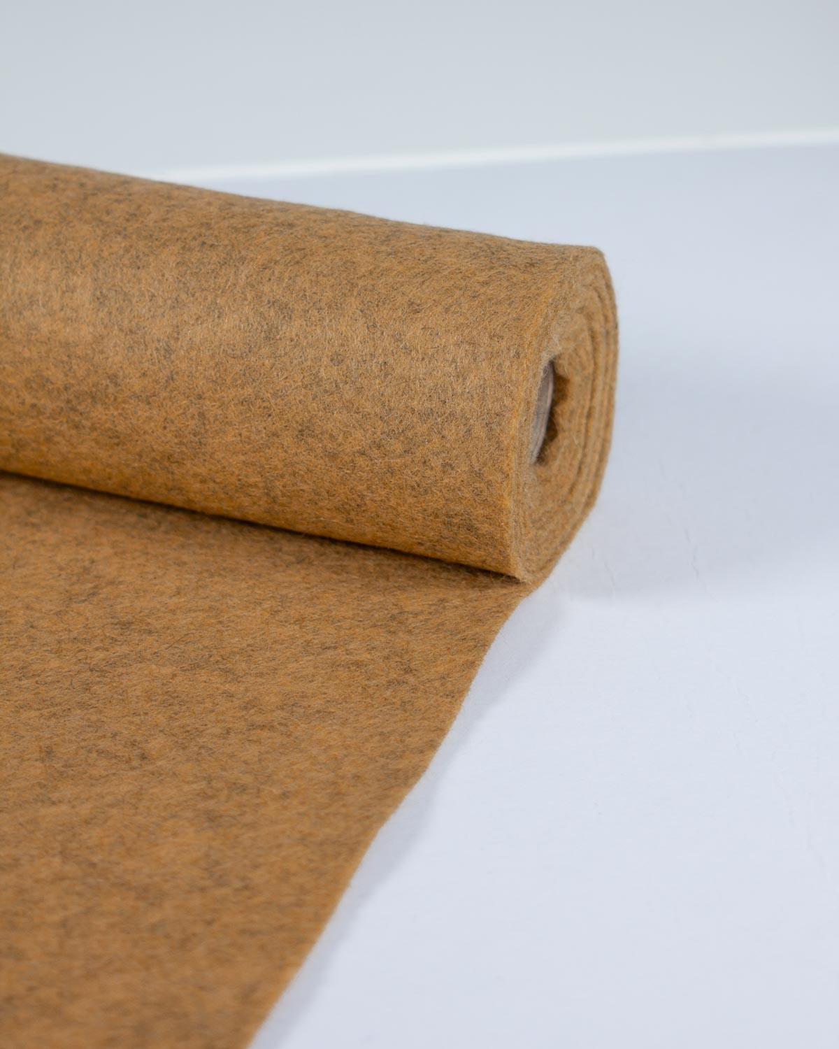 A roll of yellow gold marl wool and viscose felt fabric unrolled on a clean white surface.