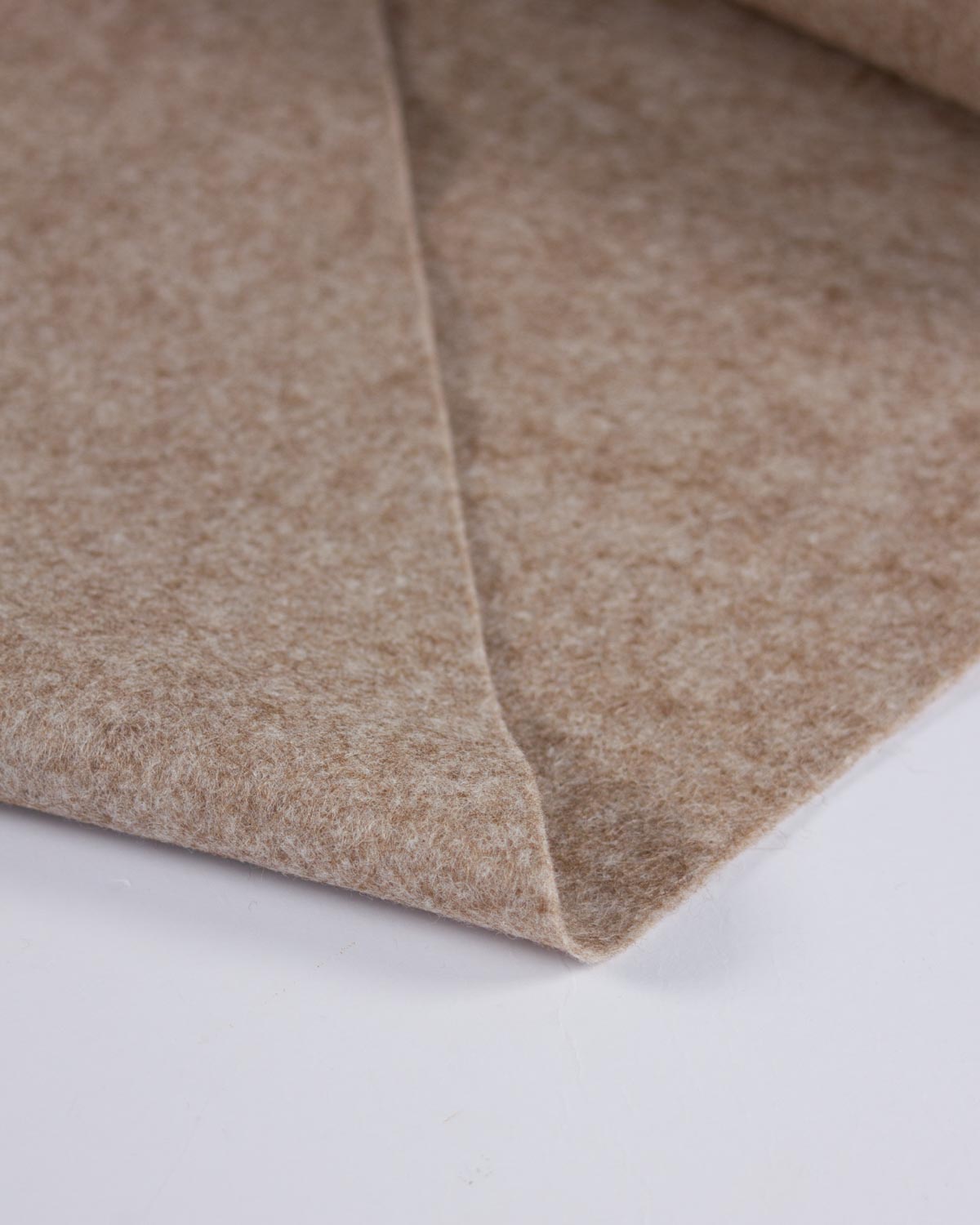 A close-up of a folded beige fawn marl wool and viscose felt fabric on a white background, showing the soft fibrous texture and folded edge.