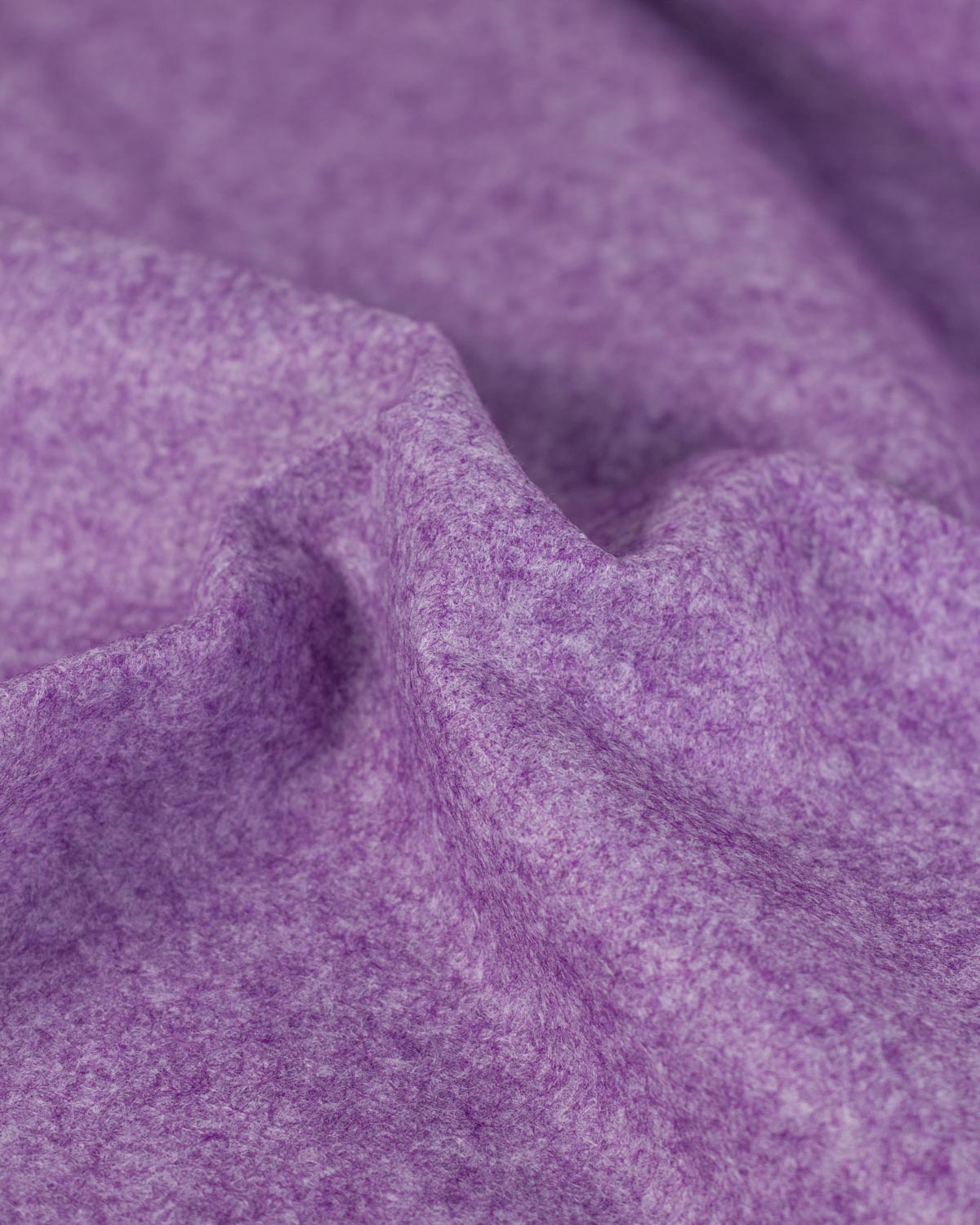 A close-up of draped heather marl purple wool and viscose felt fabric showing its soft, textured and marled surface.