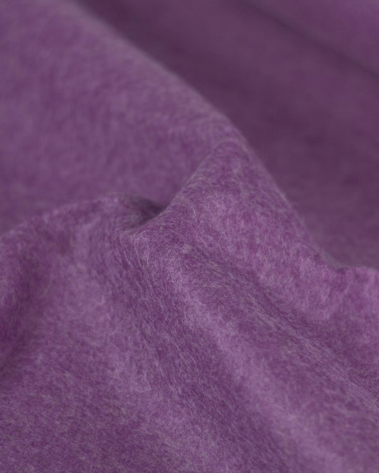A close up of a gathered piece of wool and viscose felt fabric in marl purple showcasing its marled texture and firm structure. 