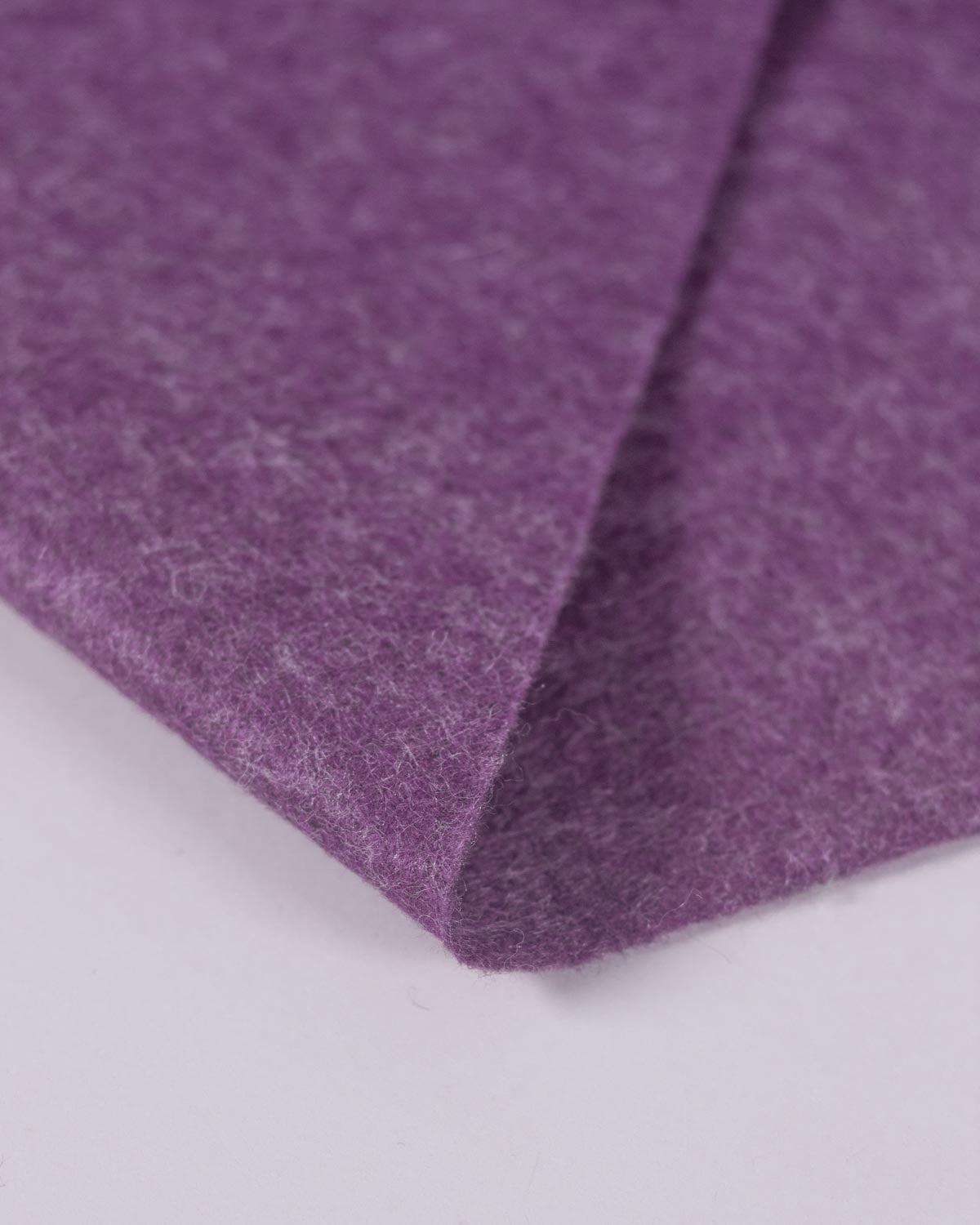 A close-up of folded purple marl wool and viscose felt fabric showing its textured, fibrous surface on a plain light background.