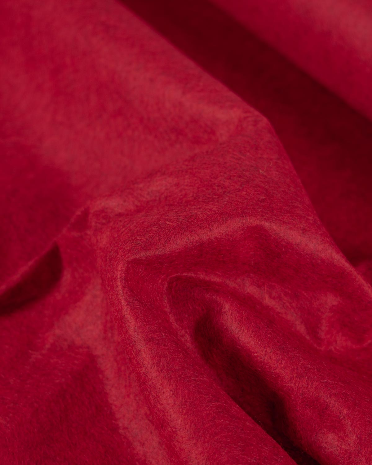 A close-up of draped red marl wool and viscose felt fabric with a soft, velvety texture and gentle folds.
