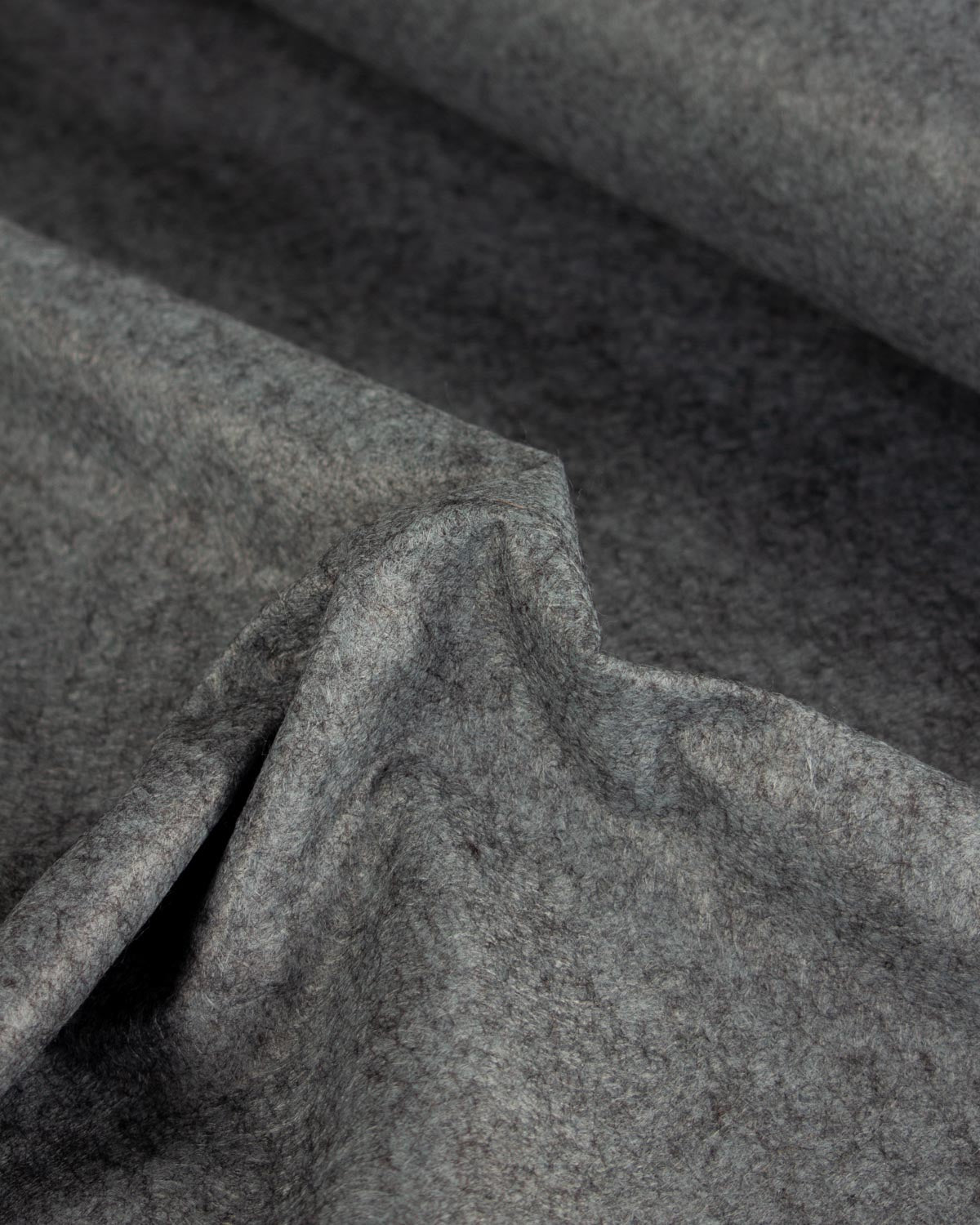 A piece of black soot coloured wool and viscose felt fabric, gathered  in a bunch to show its marl texture.