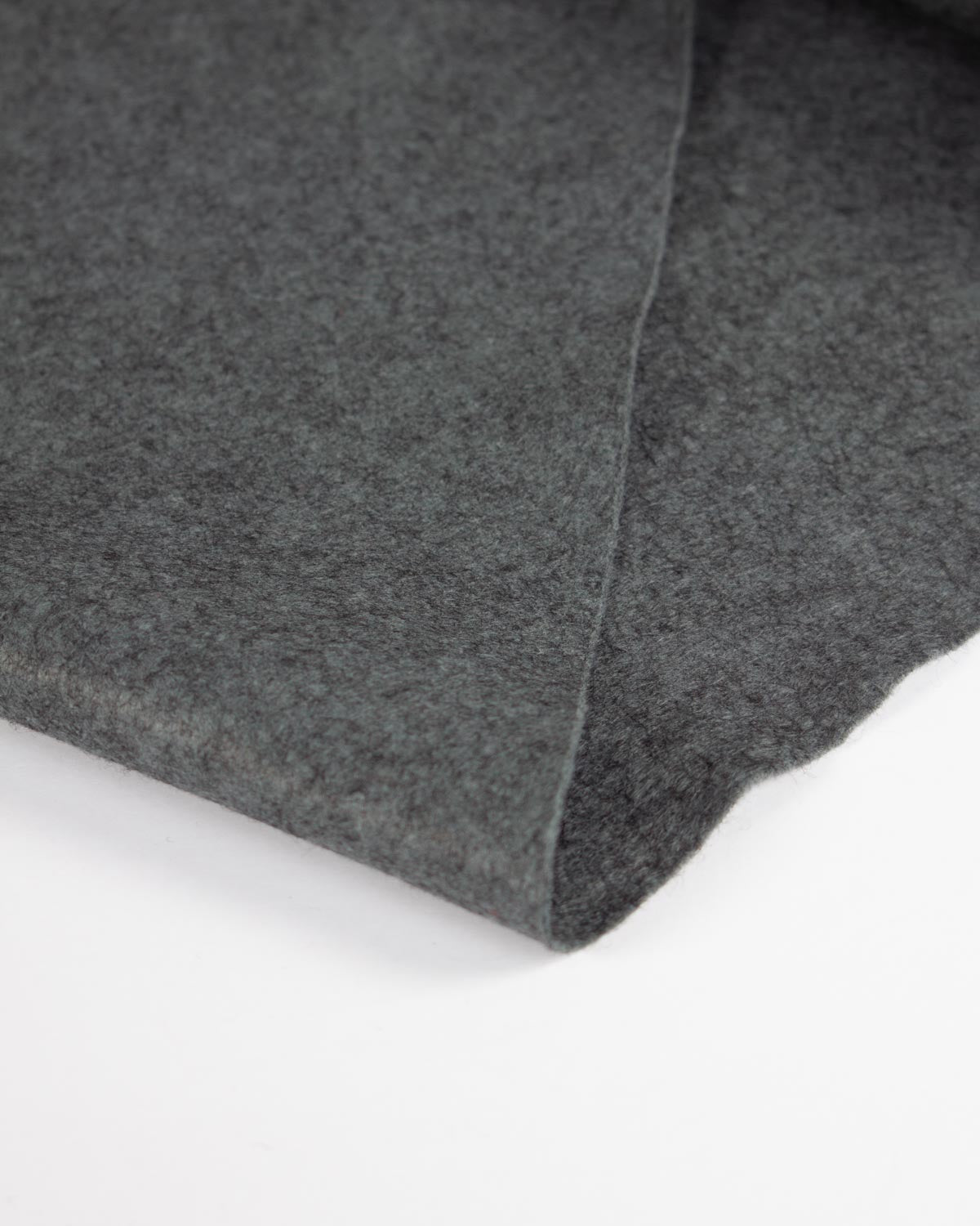 A piece of soot marl wool and viscose felt fabric folded on a flat white surface to show its textured finish.