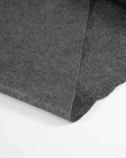 A piece of soot marl wool and viscose felt fabric folded on a flat white surface to show its textured finish.