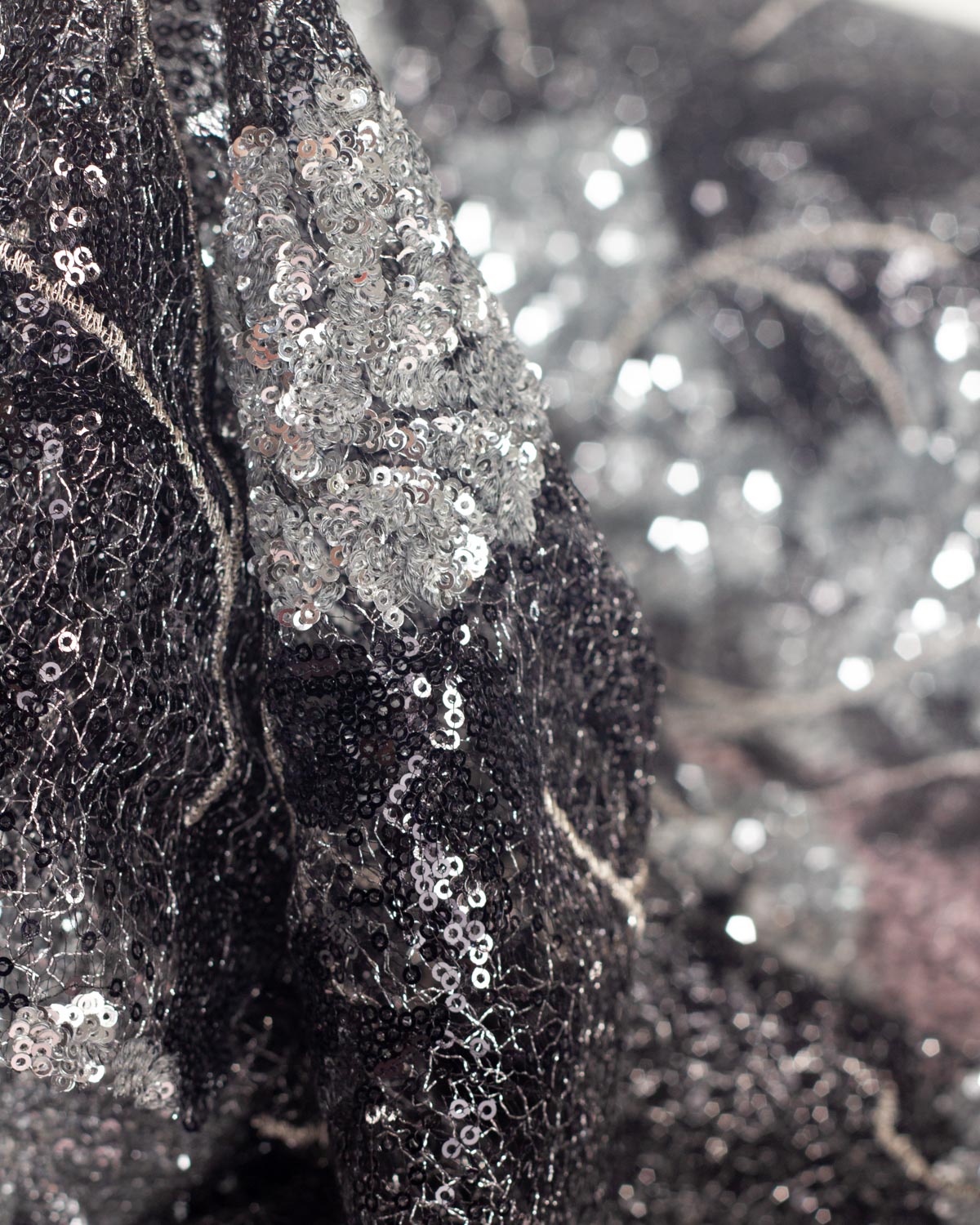 A draped piece of black and silver lurex cobweb tulle featuring a heavily sequined design in the shape of a silver monstera leaf. 