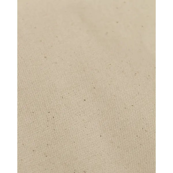 Close up of natural seeded pure cotton canvas fabric with visible seed flecks