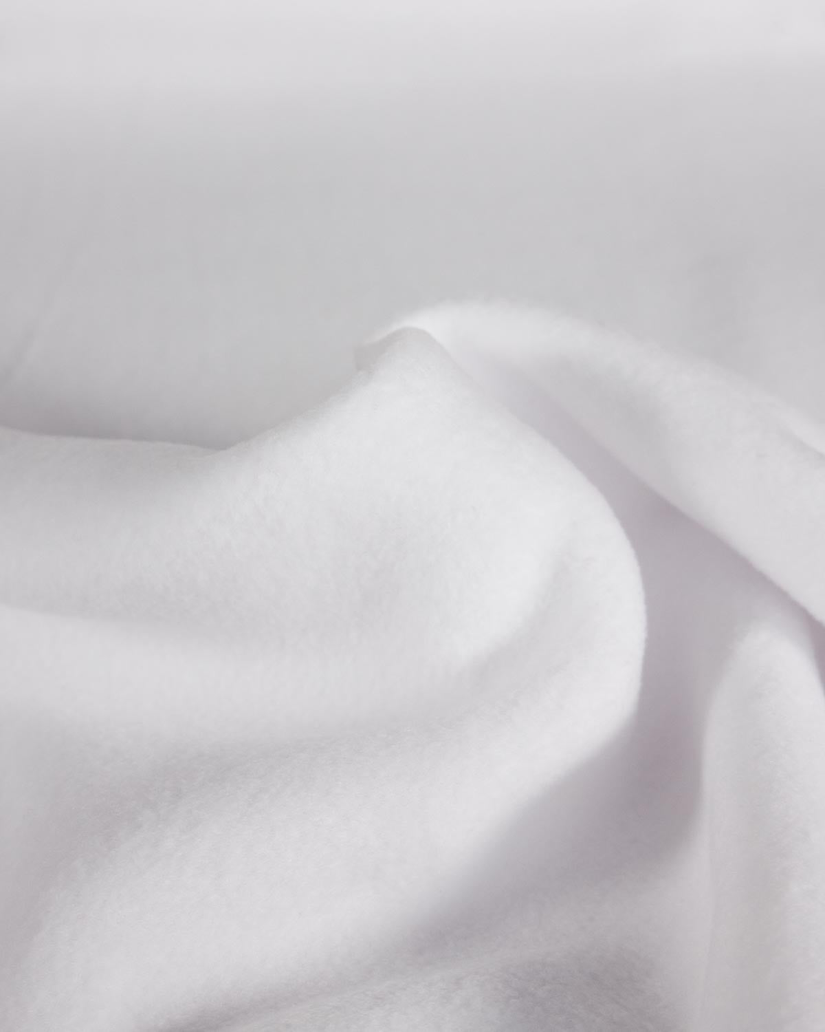 A close-up of plain white fleece fabric with soft folds and a fluffy texture.