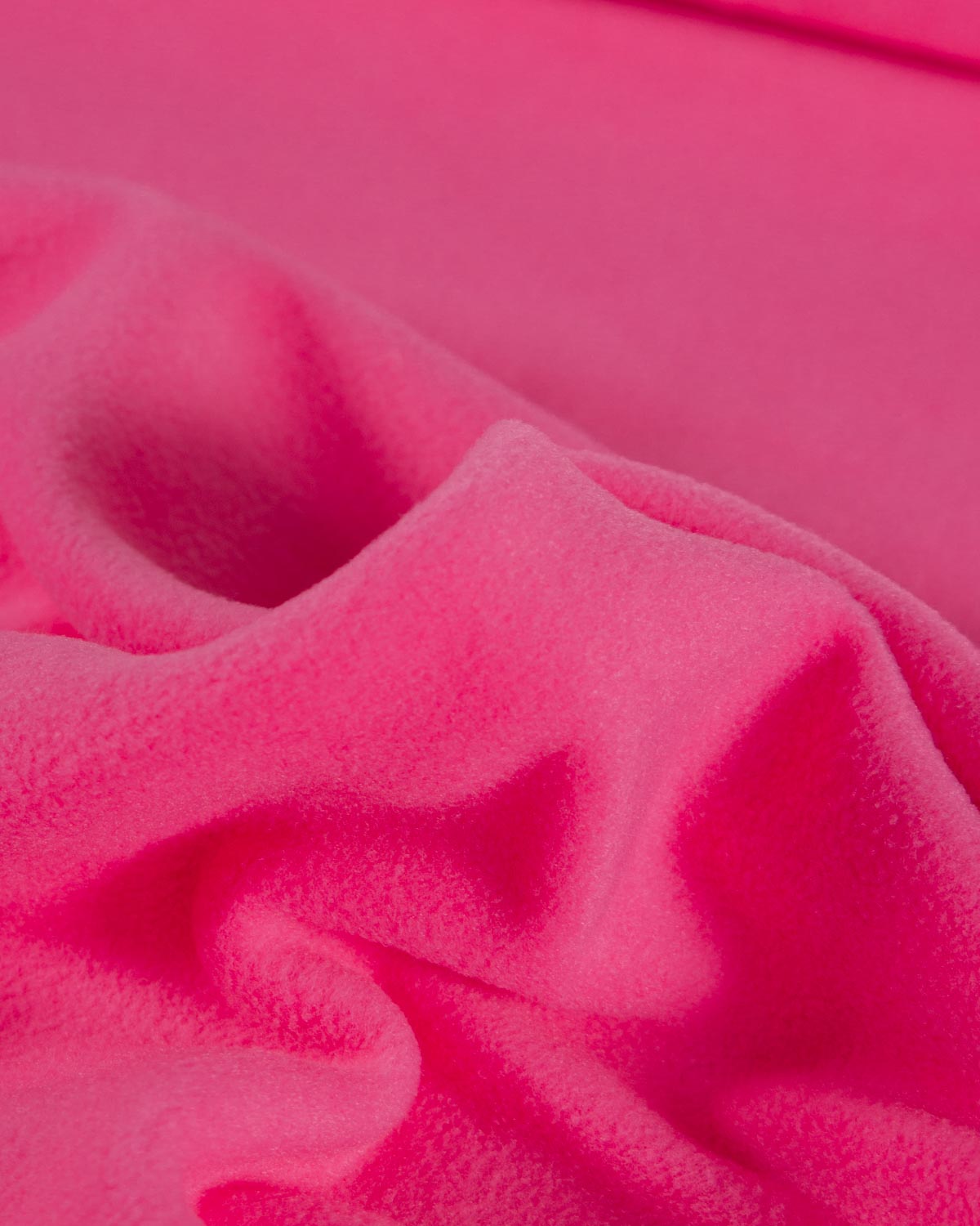 A close-up of bright hot pink fleece fabric with soft folds and a plush texture.