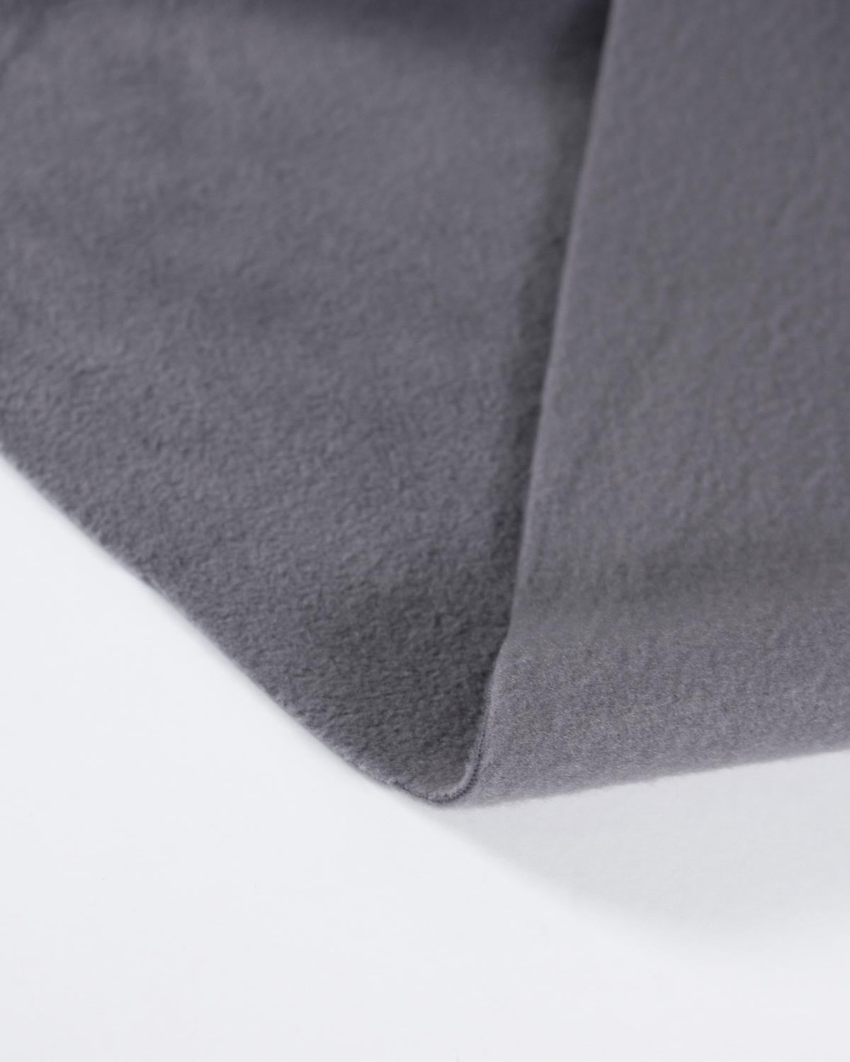 A close-up of a folded piece of dark gray fleece fabric, showing its soft texture and matte finish against a clean white background.