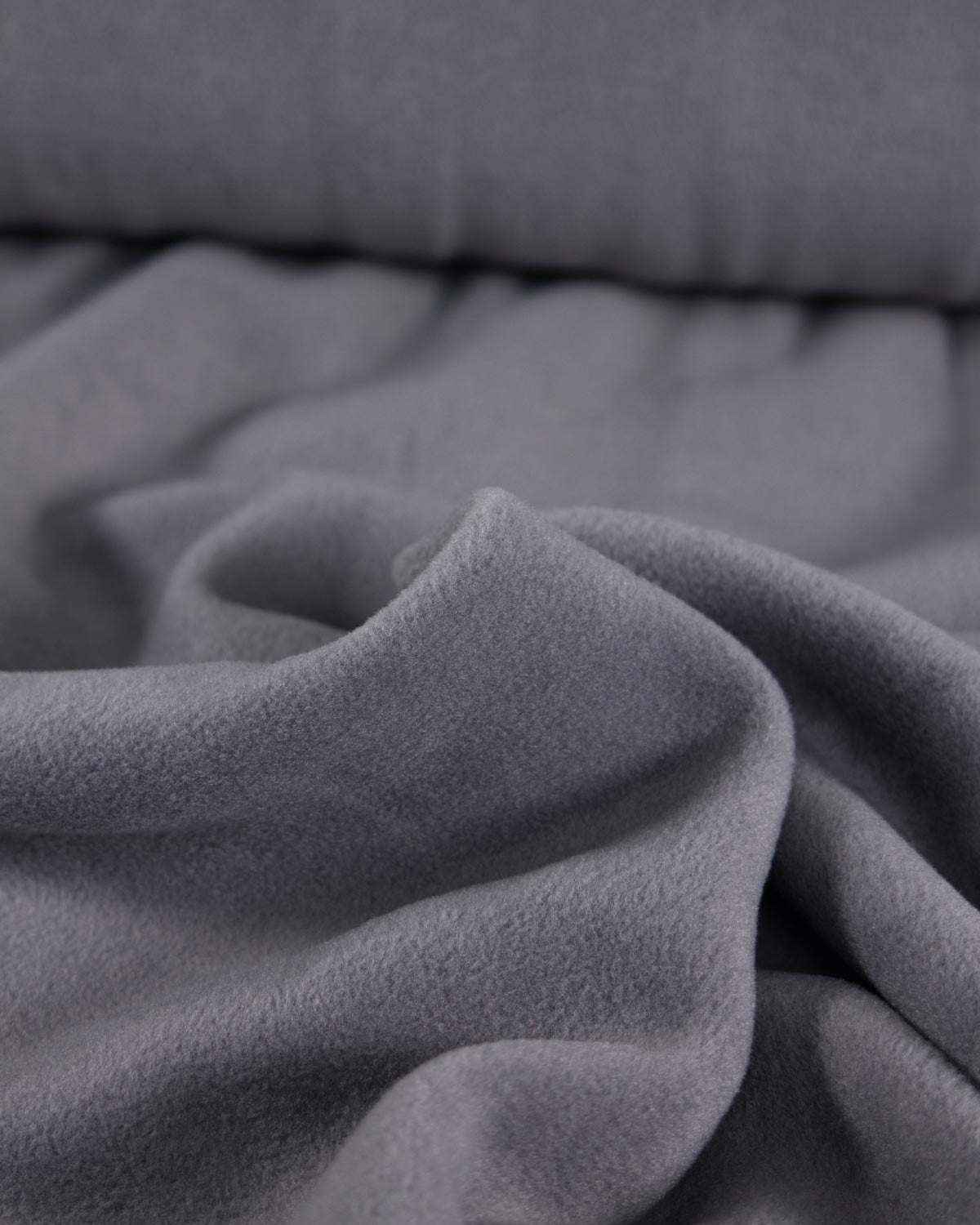 A close-up of draped grey fleece fabric with a soft, plush texture.