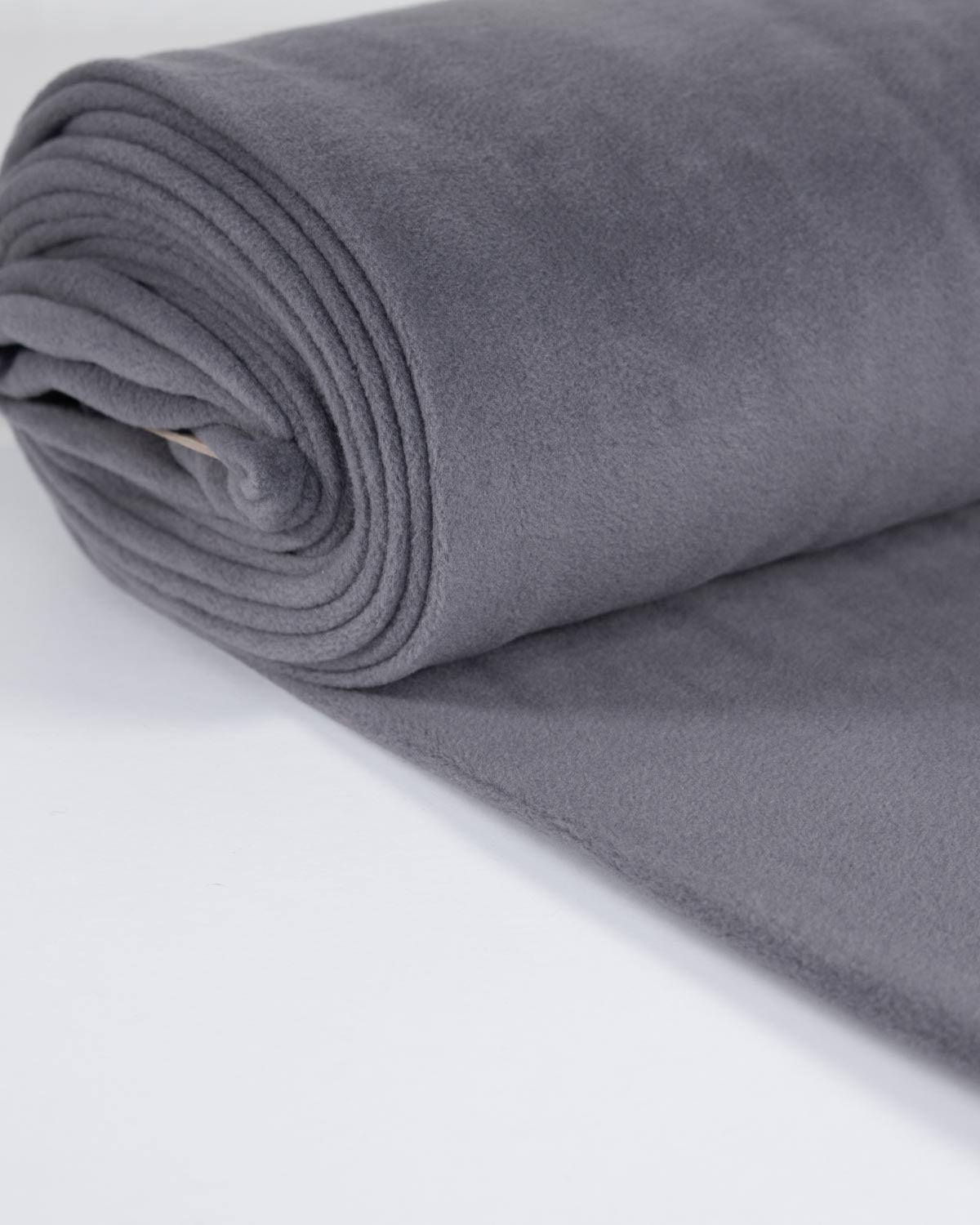 A close-up of rolled grey fleece fabric showing a soft plush texture on a plain white background.