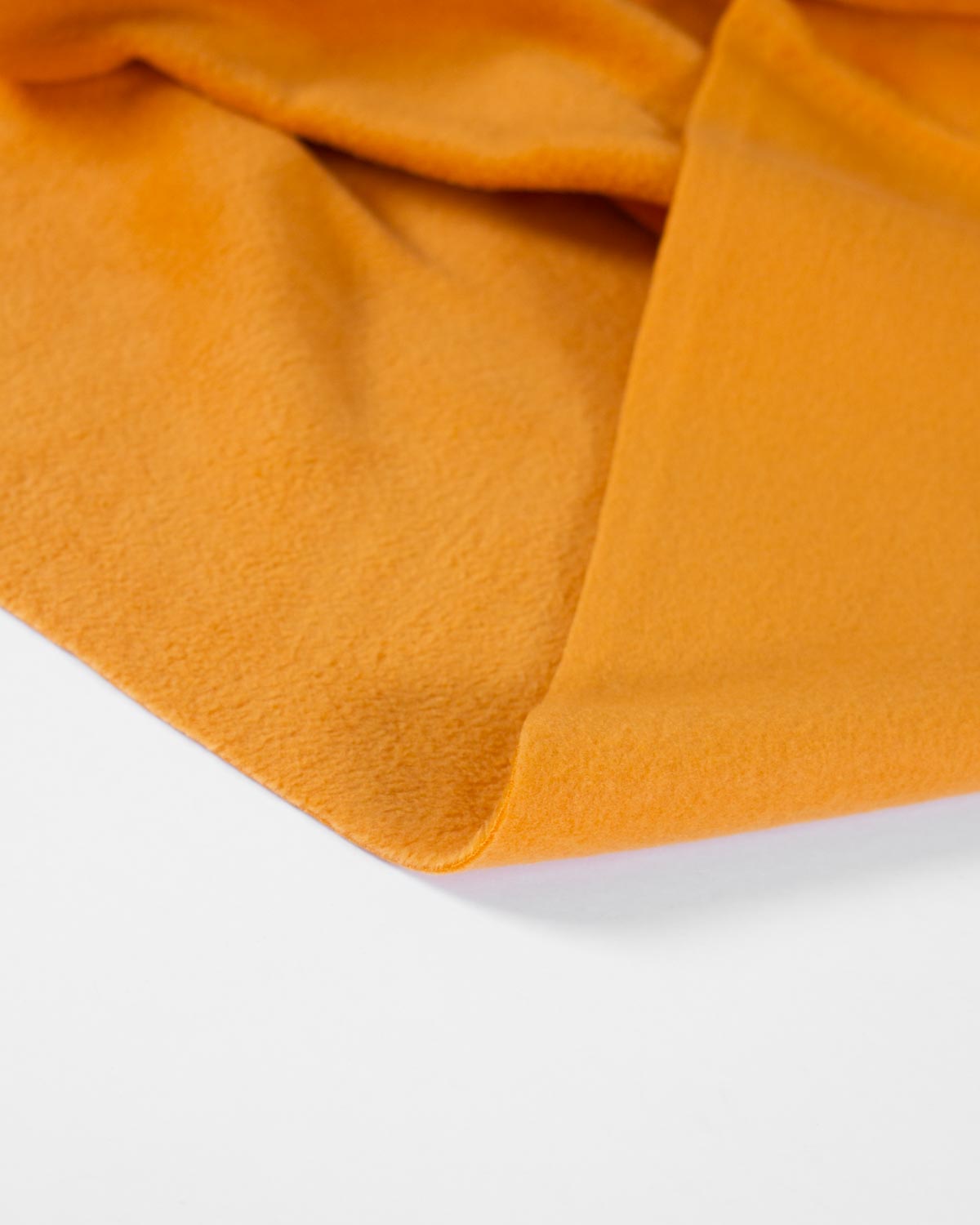 A close-up of a folded mustard yellow fleece fabric, showing its soft texture and matte finish against a clean white background.