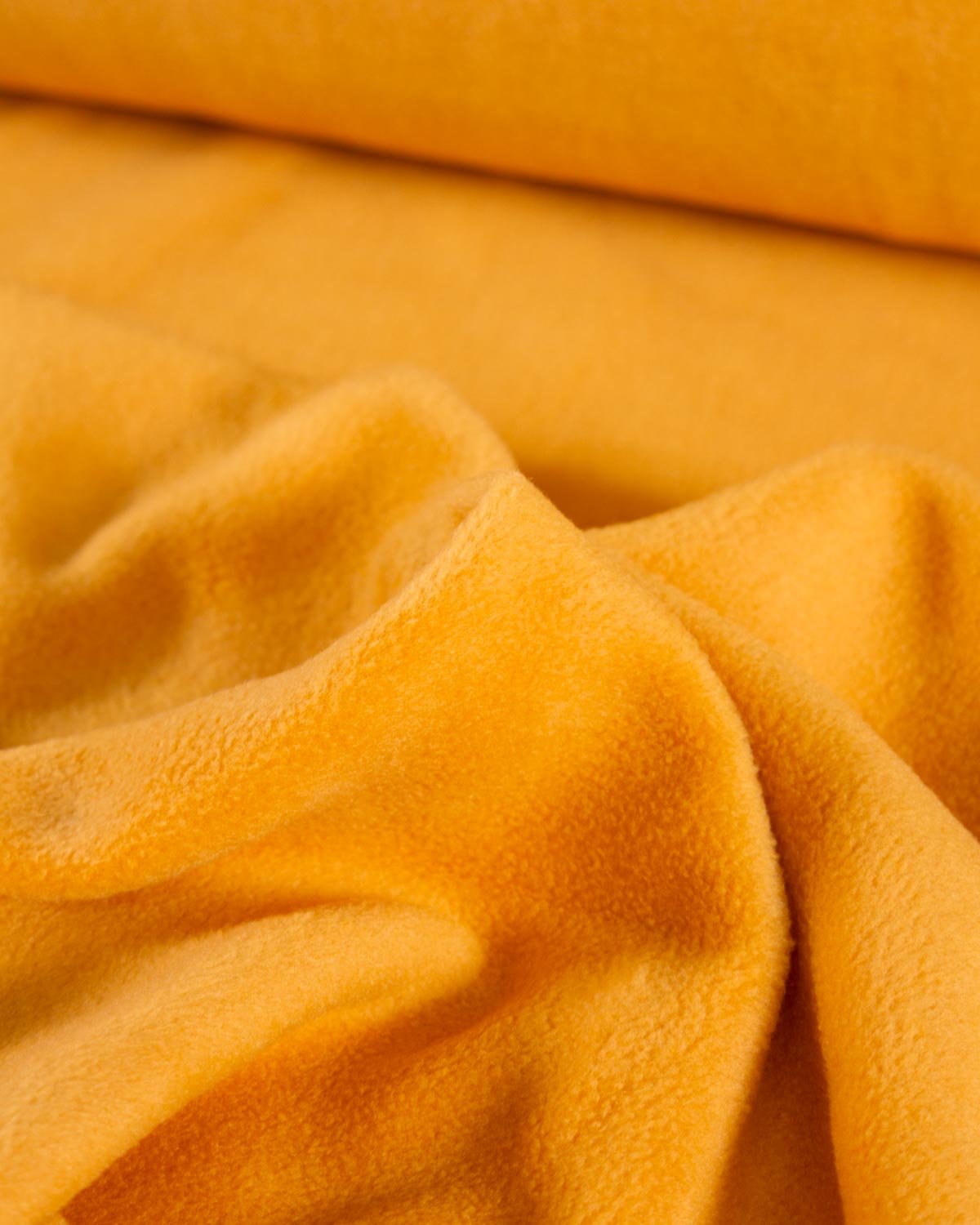 Close up of a mustard yellow soft, plush fleece fabric. 