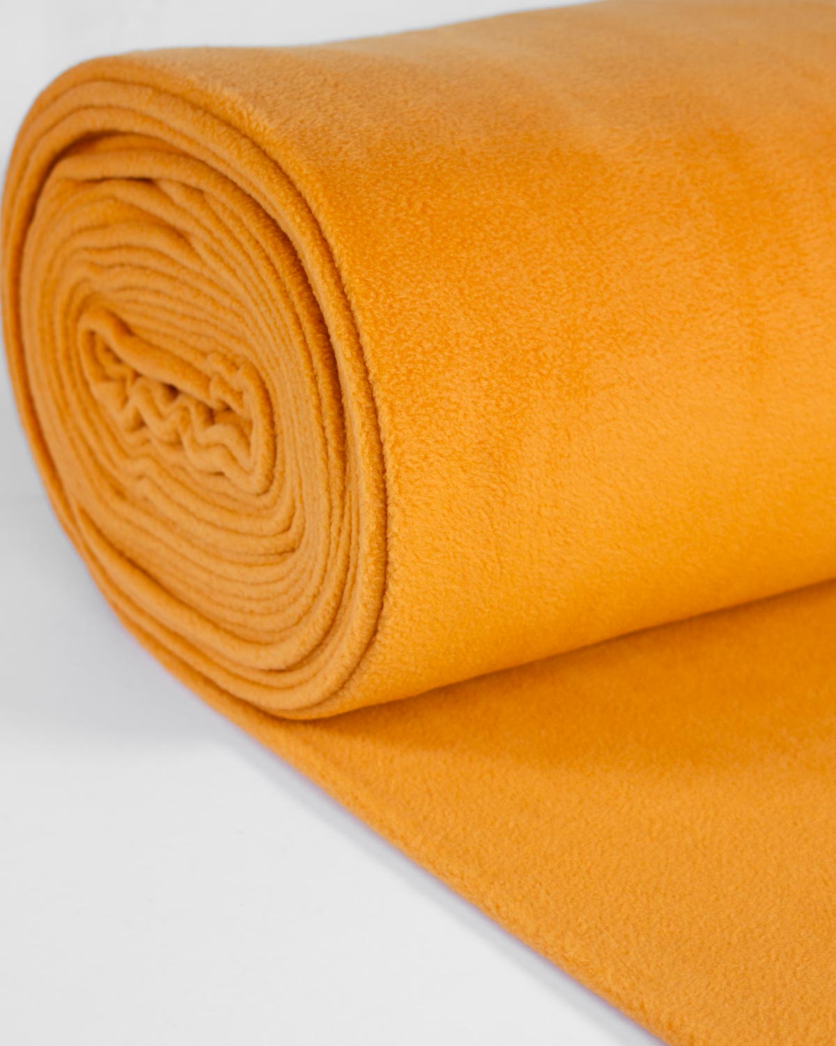 A close-up of a rolled piece of mustard yellow fleece fabric, showing its soft, textured surface, on a clean white background.
