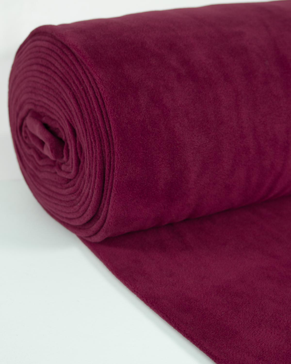A roll of deep burgundy red vfleece fabric, partially unrolled to show its soft, plush texture against a clean white background.