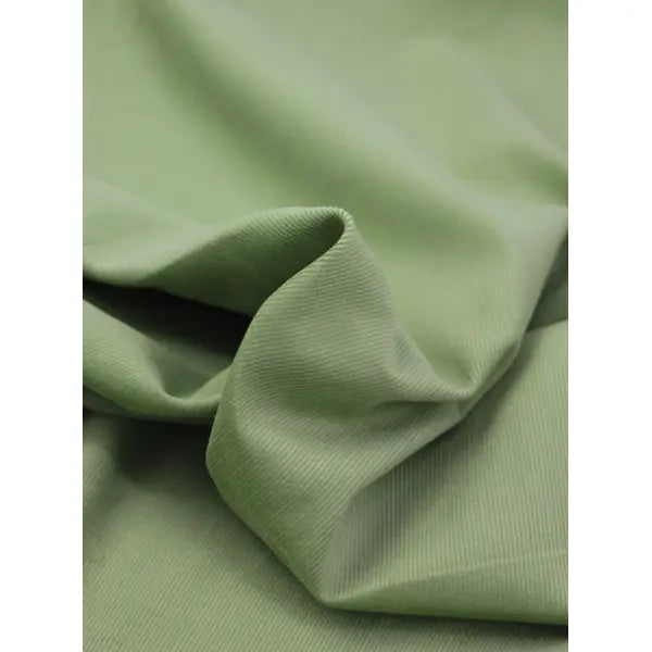 Close up of fennel green pure cotton babycord fabric with fine ribbed cord surface