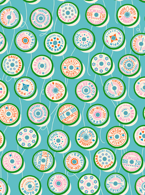Top down view of colourful thread spools on a turquoise quilting cotton