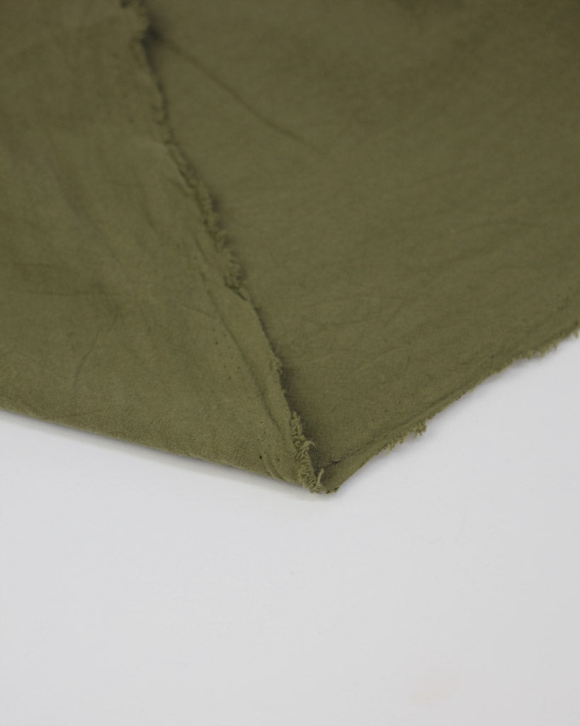selvedge edge of a washed crushed cotton fabric in soft green