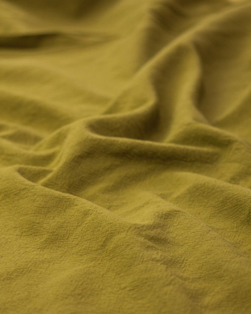 Crushed washed cotton fabric in yellow olive green