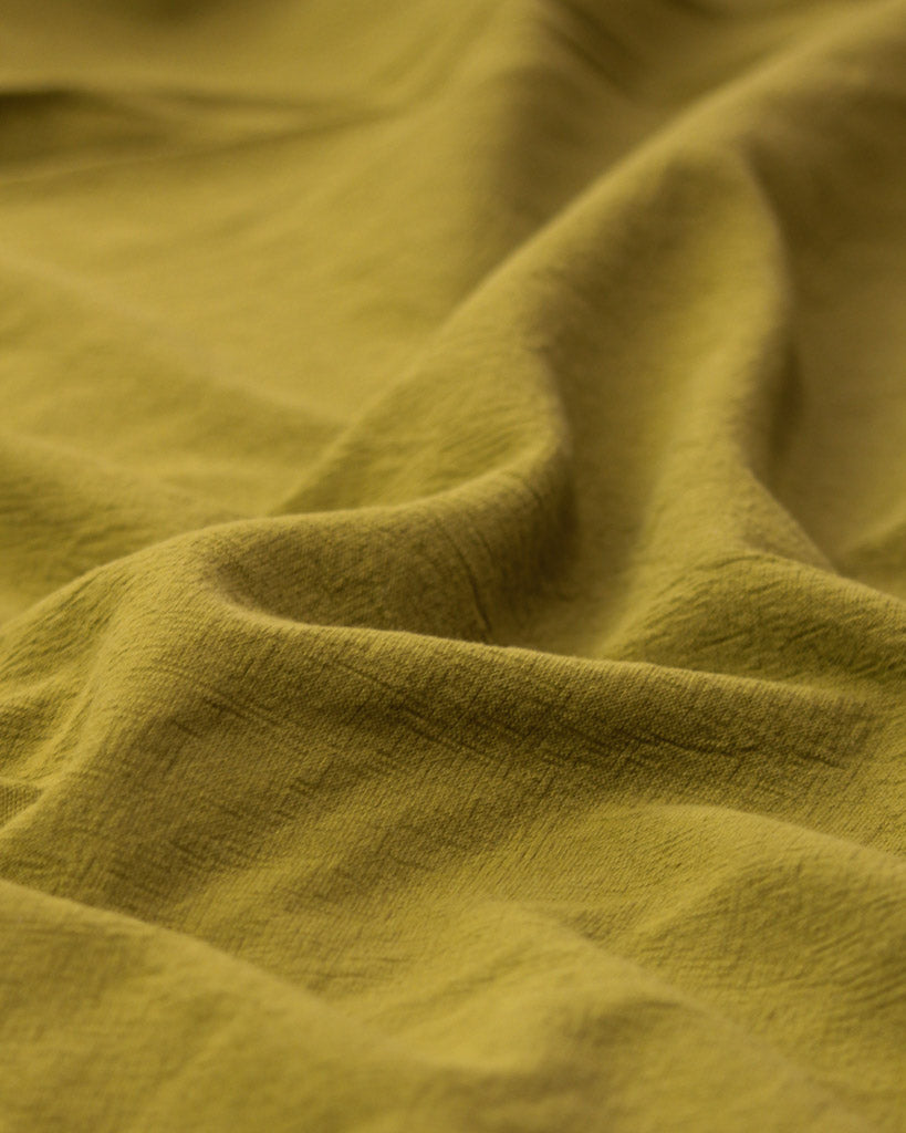 Crushed washed cotton fabric in yellow olive green