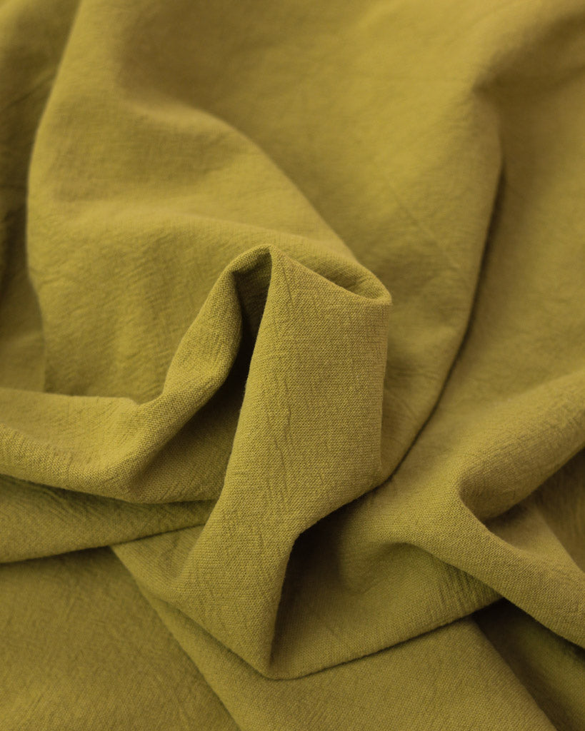 Close up of crushed washed cotton fabric in yellow olive green