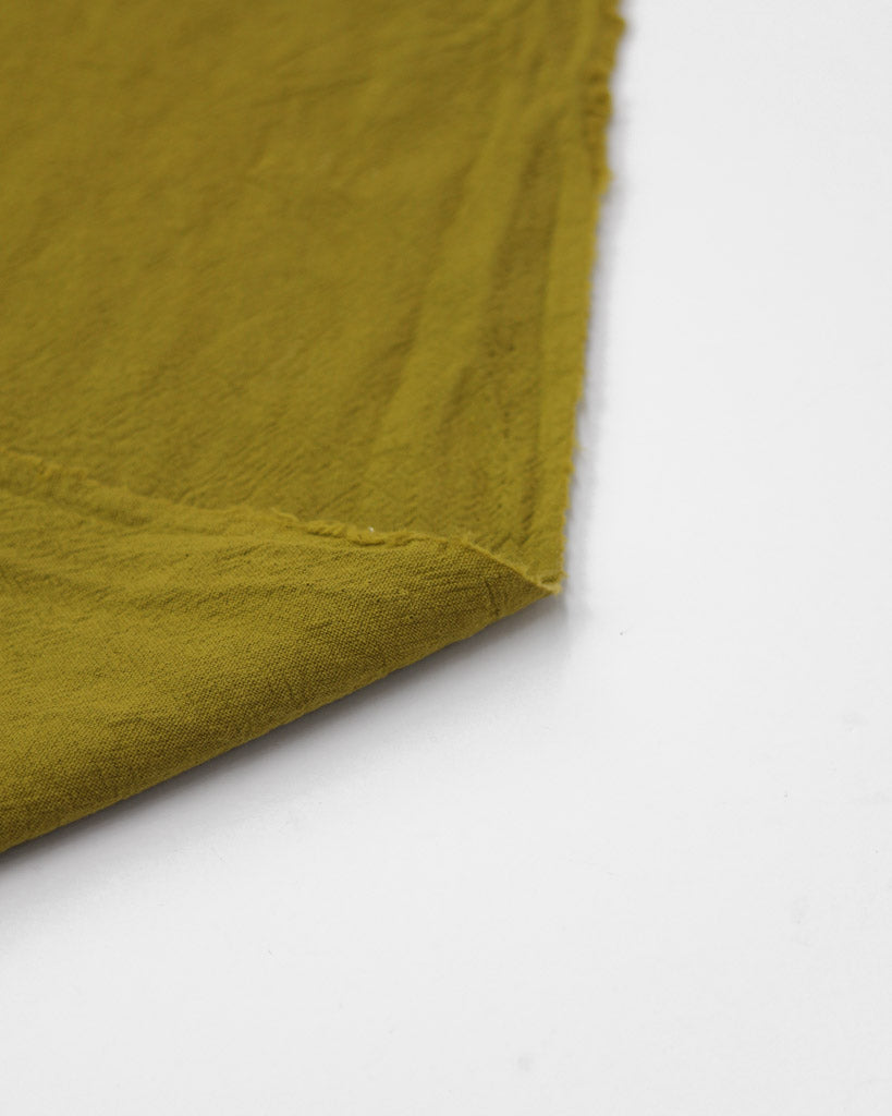 Selvedge edge of crushed washed cotton fabric in yellow olive green