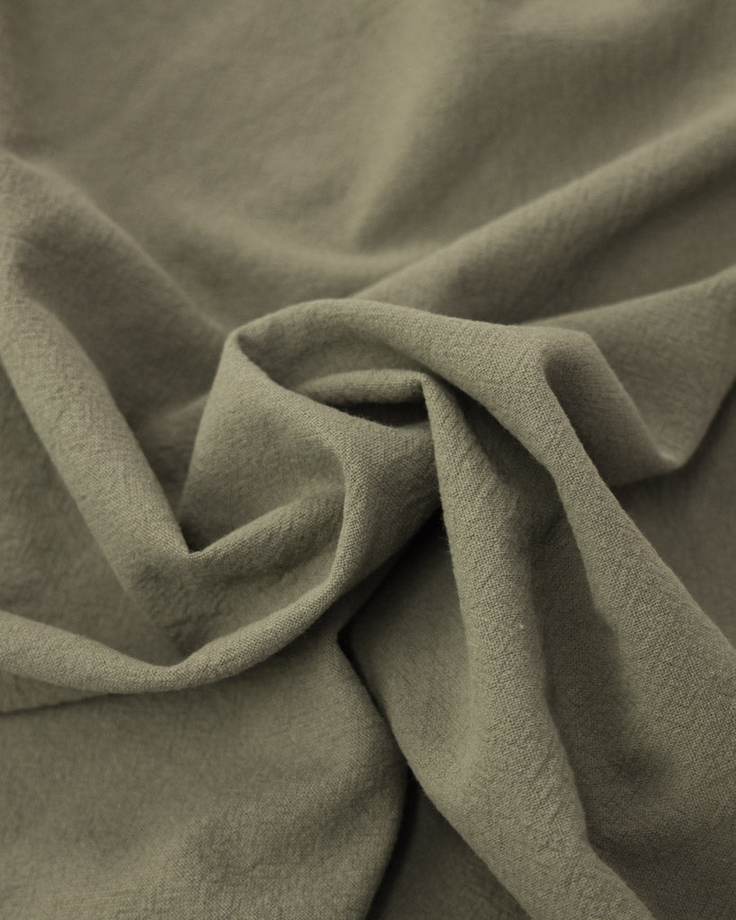 Close up of crushed washed cotton fabric in a soft grey-green