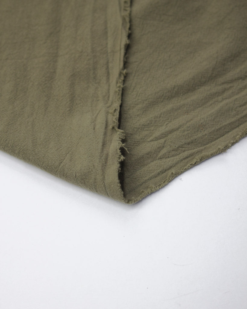 Selvedge edge of crushed washed cotton fabric in a soft grey-green