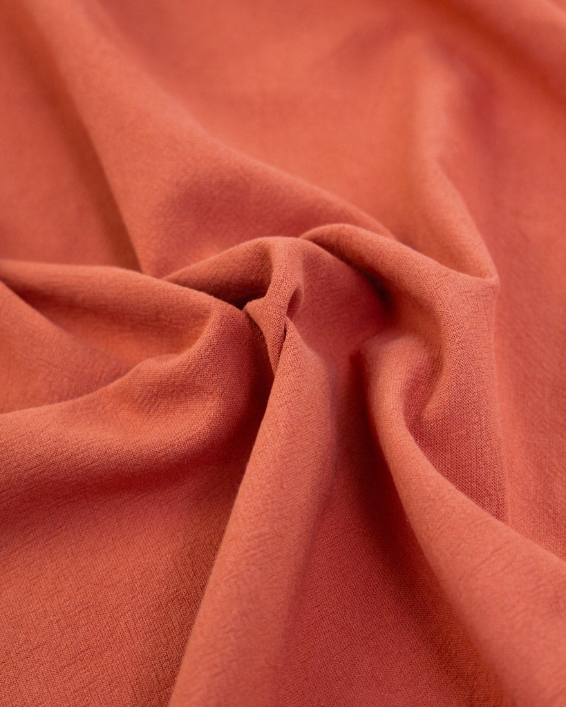 Close up of crushed washed cotton fabric in hot red-orange
