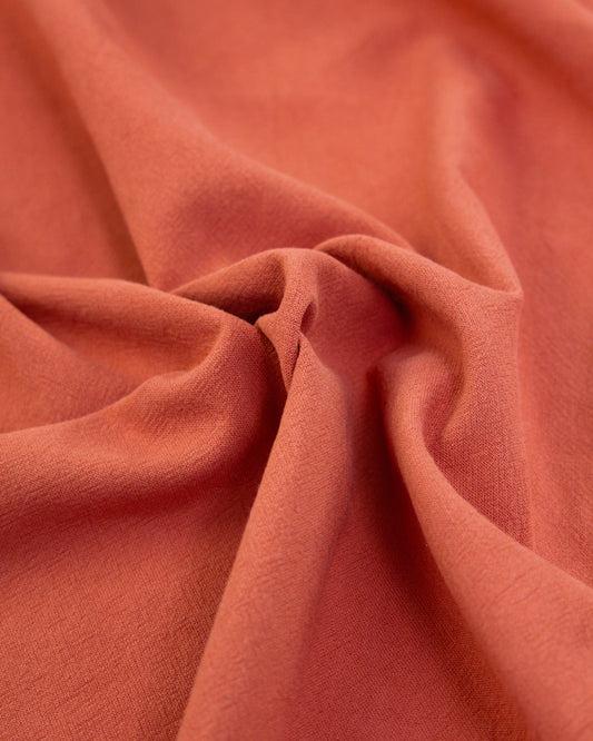 Close up of crushed washed cotton fabric in hot red-orange