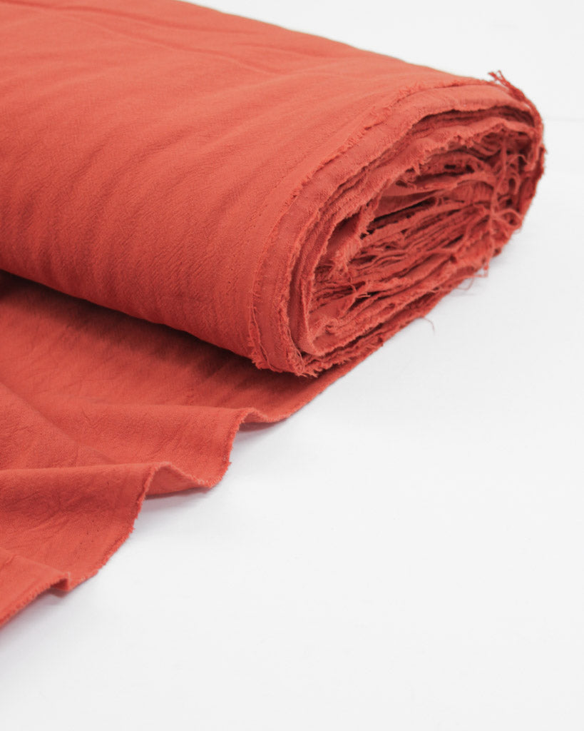 Bolt of crushed washed cotton fabric in hot red-orange
