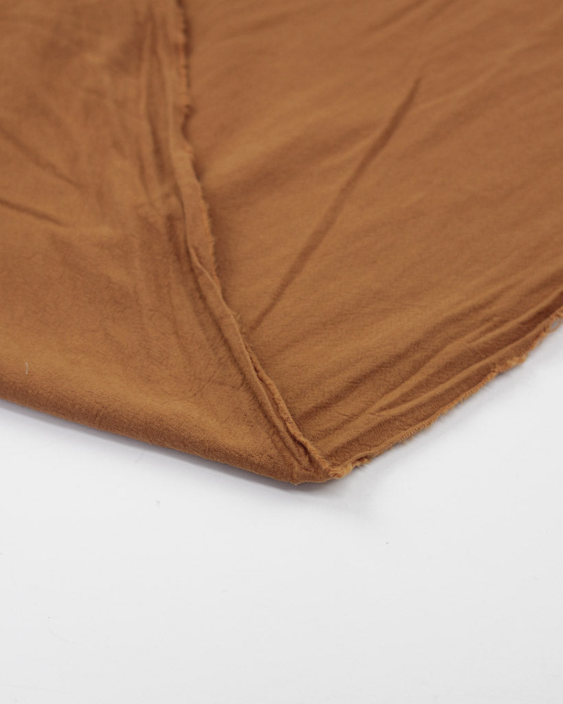Selvedge edge of crushed washed cotton fabric in ginger brown