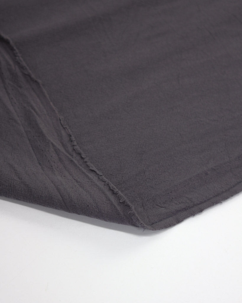 Flipped edge of crushed washed cotton fabric in dark grey