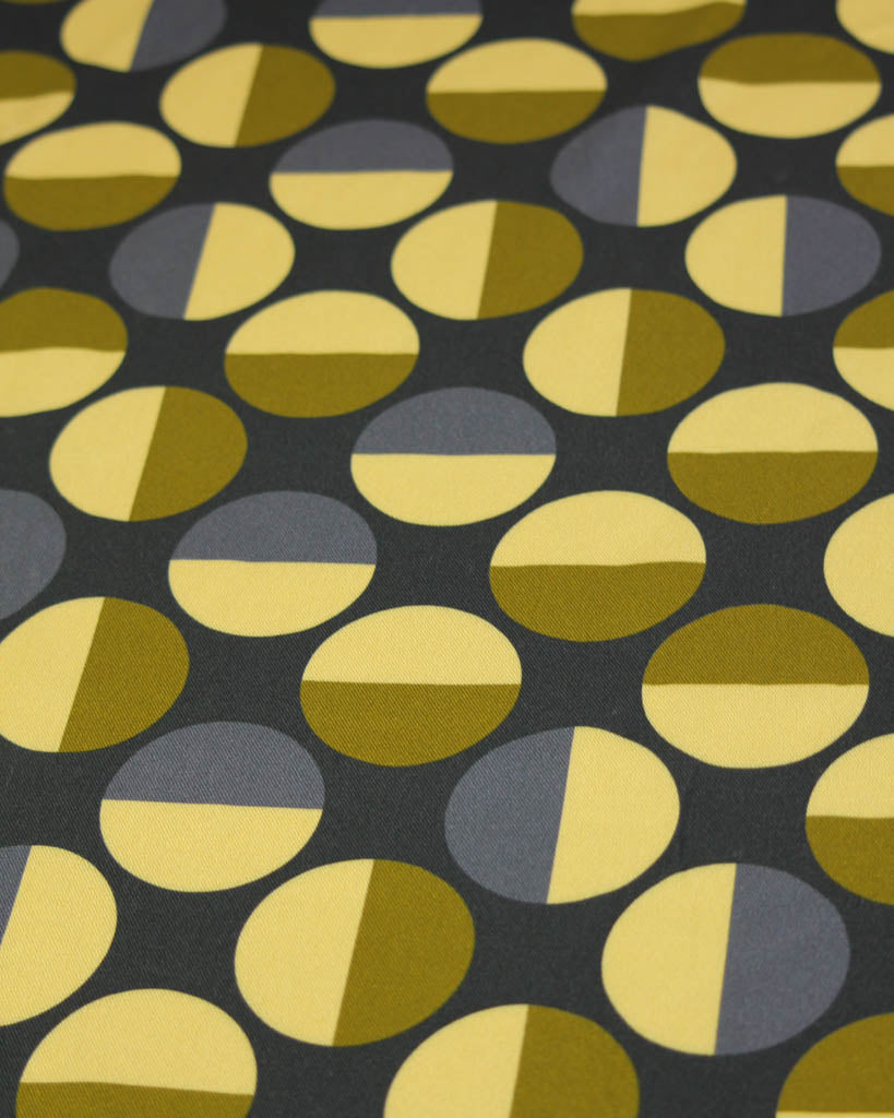 Viscose twill fabric with a pattern of greenand gray half-circle shapes on a black background