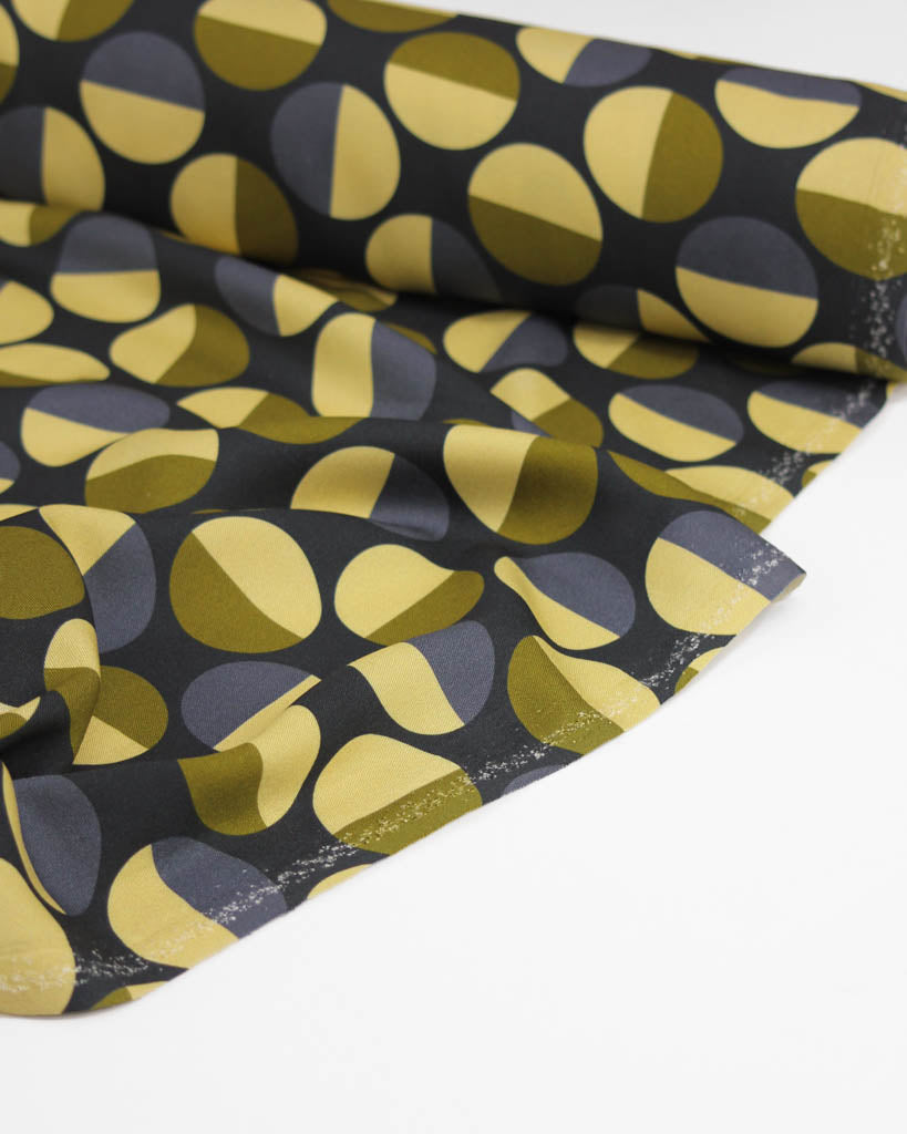 Viscose twill fabric with a pattern of yellow and green circle shapes on a black background