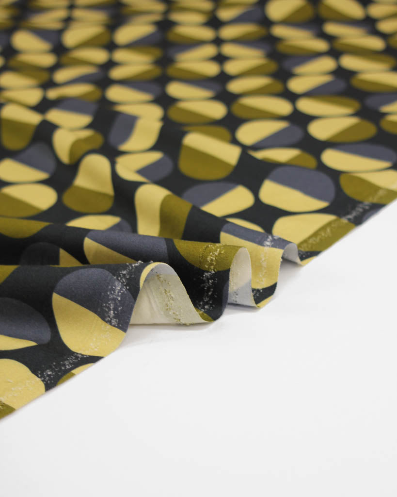 Viscose twill fabric with a geometric pattern of green and yellow circle shapes on a black background
