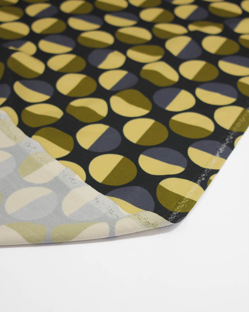Close-up of a patterned viscose twill fabric with geometric circle shapes on a black background